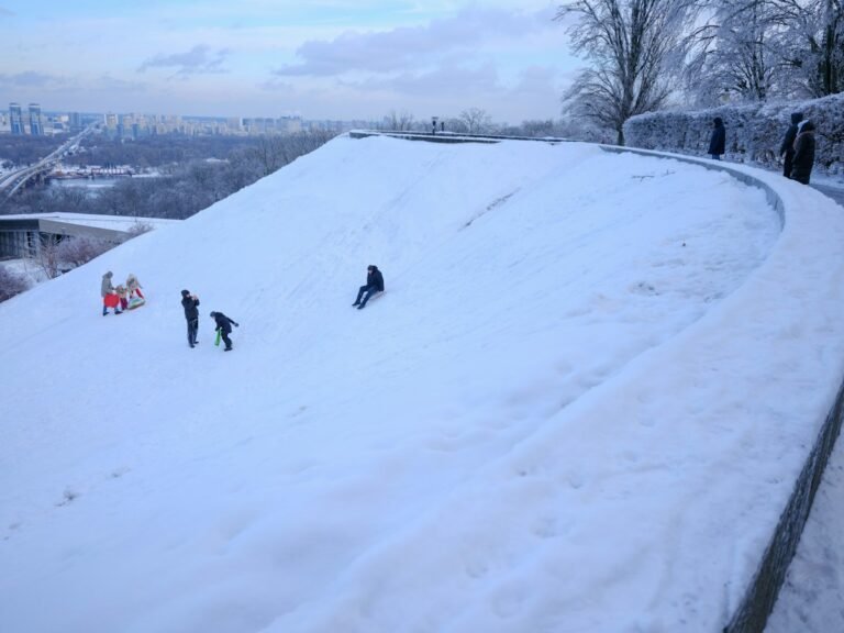 Illustrative families sledding down a snowy hill; not a specific Hudson Valley attraction