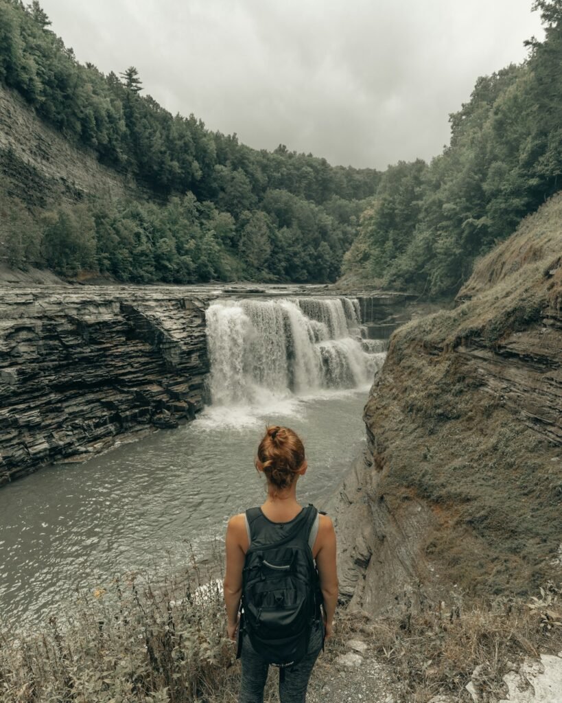 Illustrative waterfall and visitor seated on rocks; not a specific Hudson Valley venue